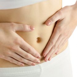 Slim woman touching her belly on white background